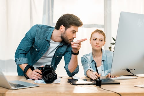 Preview: young photographers using digital devices and retouching photos at workplace