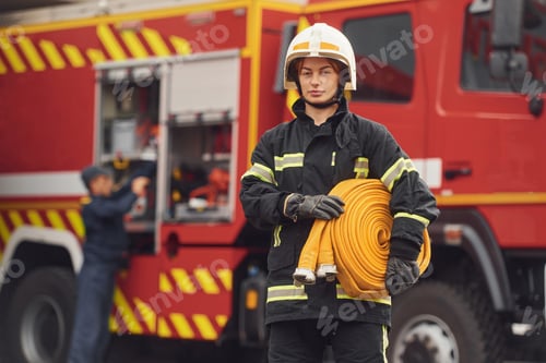 Preview: Holding fire hose. Woman in uniform is at work in department