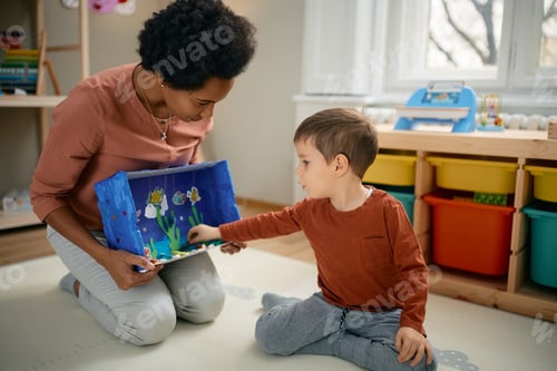 Preview: Small boy enjoying while playing with his African American kindergarten teacher.