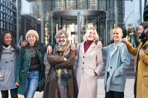 Preview: Happy team of elegant business professionals embracing and smiling outside the company workplace