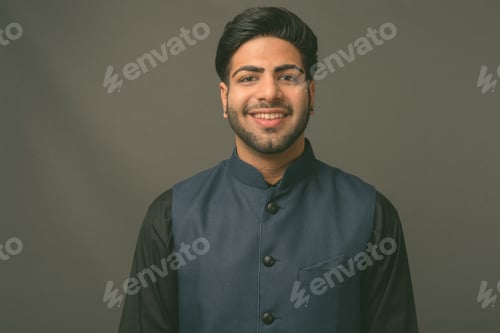 Preview: Young handsome Indian businessman against gray background