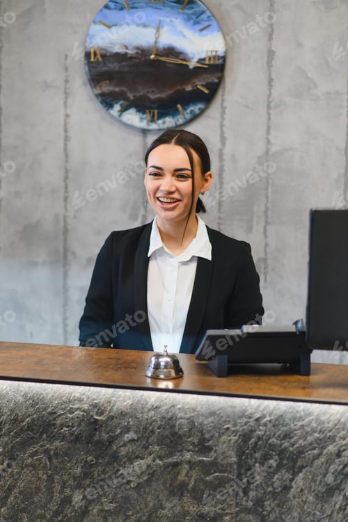 Preview: Smiling woman working as receptionist at hotel front desk