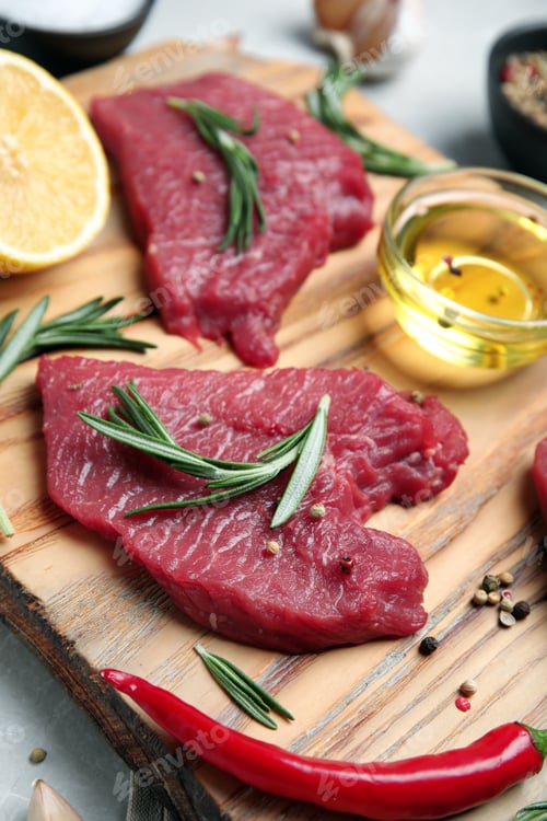 Preview: Fresh raw meat steaks and spices on wooden board, closeup