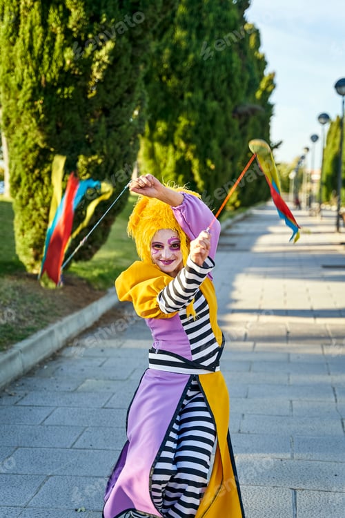 Preview: Smiling female harlequin juggling poi in park