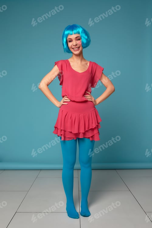 Preview: Close up of a flirtatious female model on blue background wearing a blue wig. Pretty glamorous woman