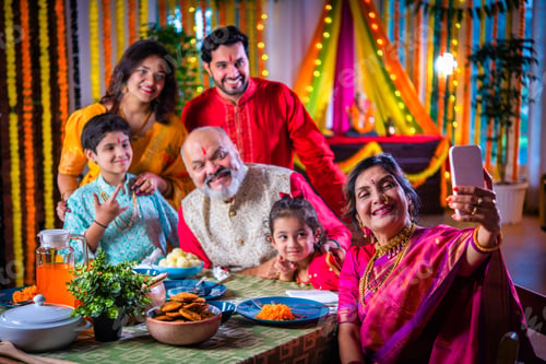 Preview: Portrait of happy Indian family in traditional outfit celebrating Diwali at home eating food