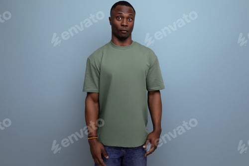 Preview: young handsome african guy with short haircut dressed in a basic t-shirt against the background with