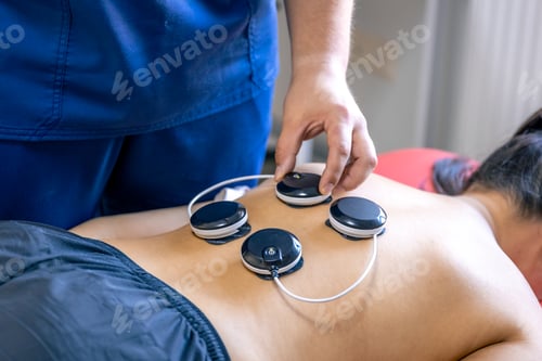 Preview: Woman receiving myostimulation treatment in physical therapy clinic.