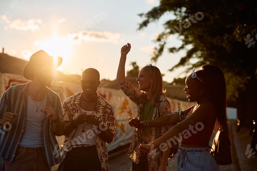 Preview: Carefree people dancing on summer music festival at sunset.