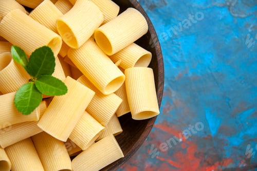 Preview: Half shot of dinner preparation with pasta noodles with green in a brown pot on blue background