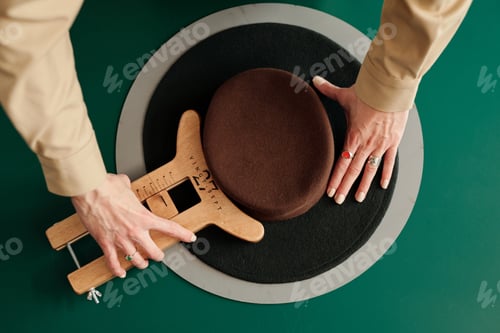 Preview: Above angle of pork pie hat and hands of craftswoman with wooden tool