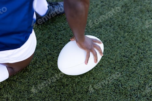 Preview: African American young male athlete holding a rugby ball on field outdoors, on grass, copy space