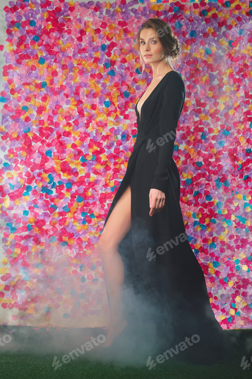 Preview: Gorgeous young lady walking in long evening cocktail dress with deep cut and vibrant makeup