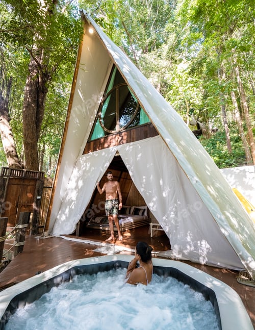 Preview: couple man and woman in tent with jaccuzzi in the jungle rain forest, luxury glamping