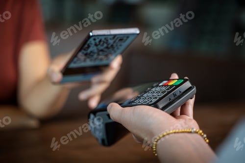 Preview: Close up woman hand holding using smartphone while making contactless payment at cafe.