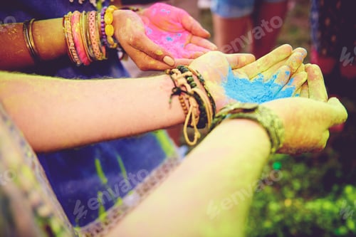 Preview: Pink and blue chalk cupped in young couples hands at festival