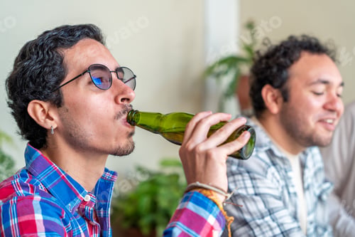 Preview: Young man drinking beer with friends at home gathering