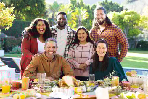 Preview: Happy diverse male and female friends posing during thanksgiving celebration meal in sunny garden