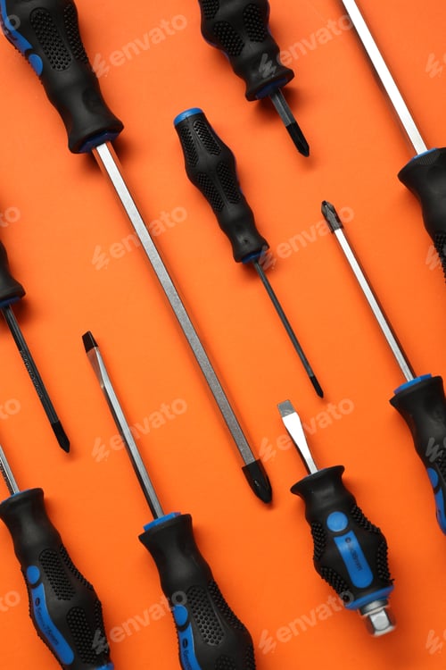 Preview: Set of screwdrivers on orange background, flat lay