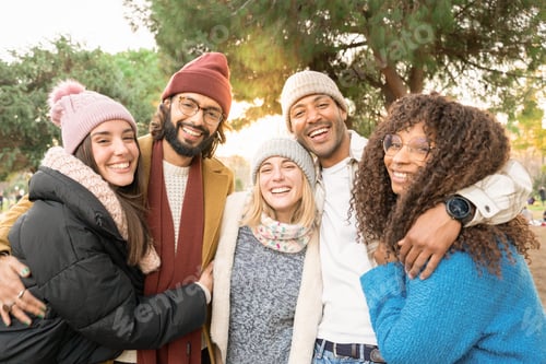 Preview: Group of friends looking at camera smiling outdoors in a park in winter.