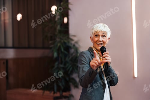 Preview: Portrait of a mature woman giving the lecture and a speech, using a microphone.