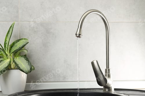 Preview: Water saving concept. Stream of water flowing from tap indoors, closeup