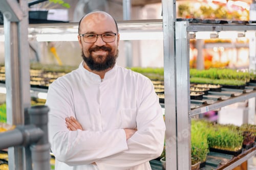 Preview: gardener in glasses and white coat at microgreen farm Healthy vegan food Organic plant germination