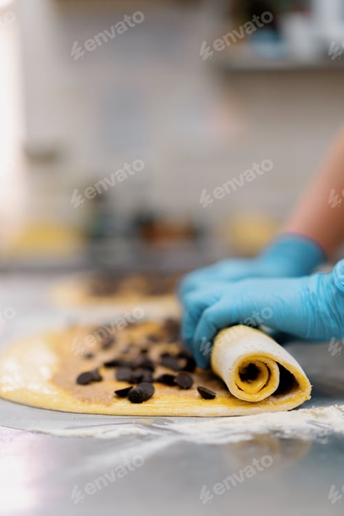 Preview: The kitchen in the bakery the process of making cinnabons woman baker uses chocolate in granules