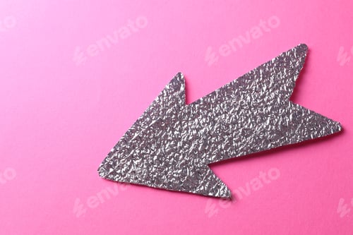 Preview: Silver tinfoil arrow on pink background, top view. Space for text