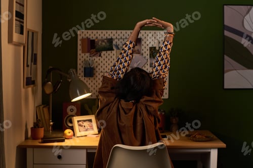 Preview: Young Woman Stretching Arms While Sitting at Desk Working
