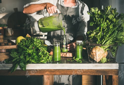 Preview: Woman pouring green smoothie from blender to bottle
