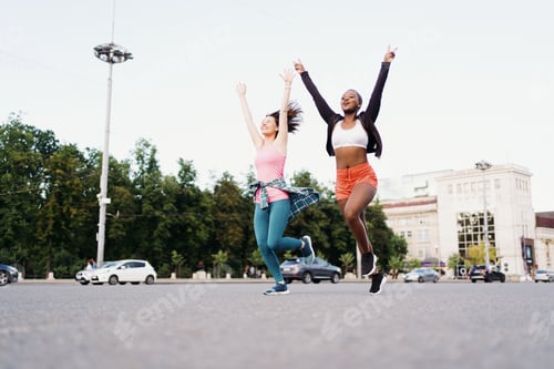 Preview: Two cheerful women running in the city outdoors. Sports, healthy lifestyle training. Diverse people