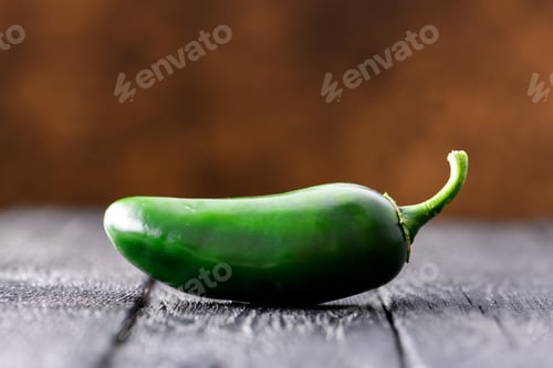 Preview: Single green jalapeno hot pepper on rustic wooden table