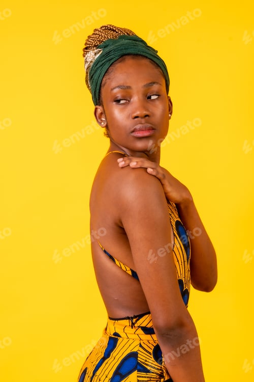 Preview: African young woman in the studio on a yellow background, traditional costume, vertical photo