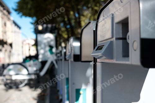 Preview: Detail of an e-bike dock station with an out of focus bikes far away.