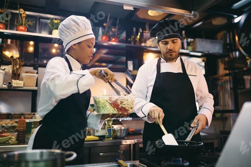 Preview: Professional cooks cooperating while preparing food in a restaurant.