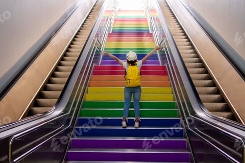 Preview: girl climbs the stairs with lgbt flag on gay pride day.