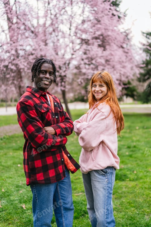 Preview: Multiracial young couple smiling in a park with blooming trees