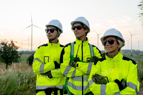 Preview: Portrait group of wind turbine workers or technicians stand with arm crossed and look to their right