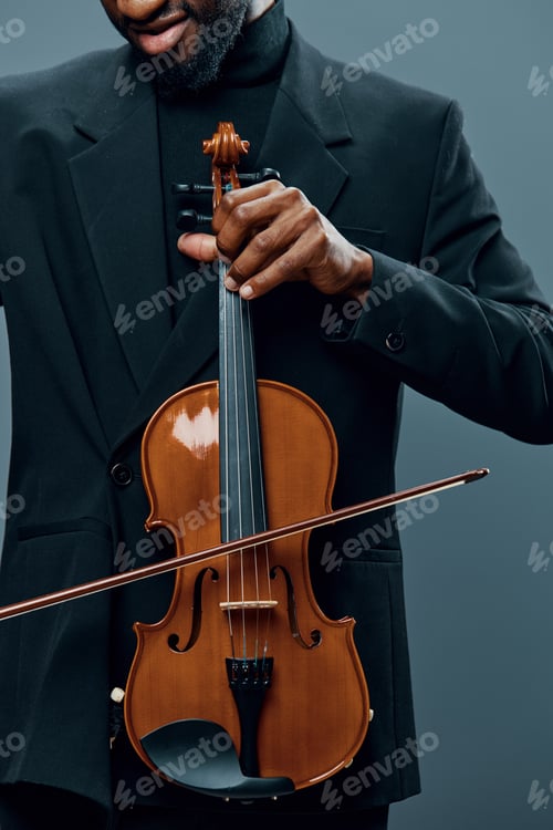 Preview: Elegant African American man holding a violin in a stylish suit against a neutral gray background