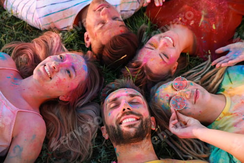 Preview: Happy friends covered with colorful powder dyes on green grass outdoors. Holi festival celebration