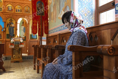 Preview: Mature woman sitting on wooden bench in church