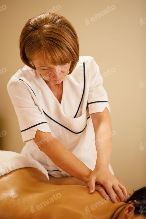 Preview: Female therapist massaging customer's back at spa salon.