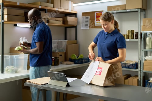 Preview: Caucasian Woman and Black Man Packing Food Donations in Community Pantry