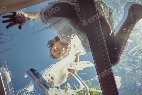 Preview: Cheerful boy washing window of car