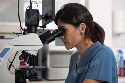 Preview: side view of female veterinarian looking through the microscope of the microscope.