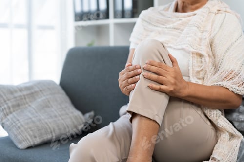 Preview: Elderly woman experiencing knee pain, holding leg