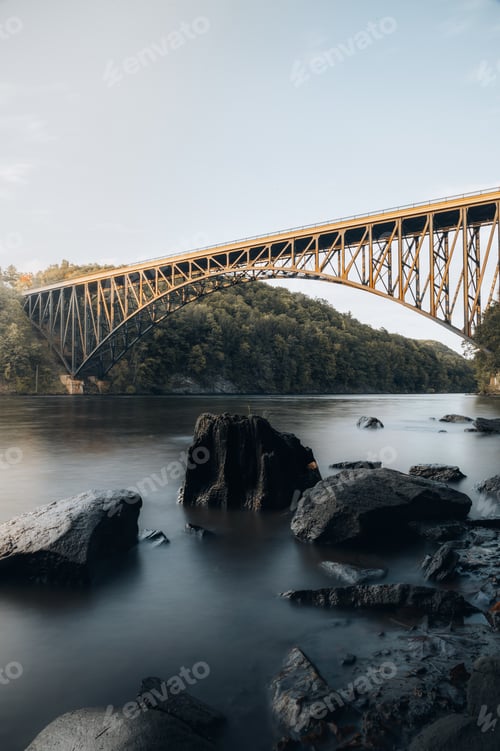 Preview: Bridge over the river in an autumn forest during sunset