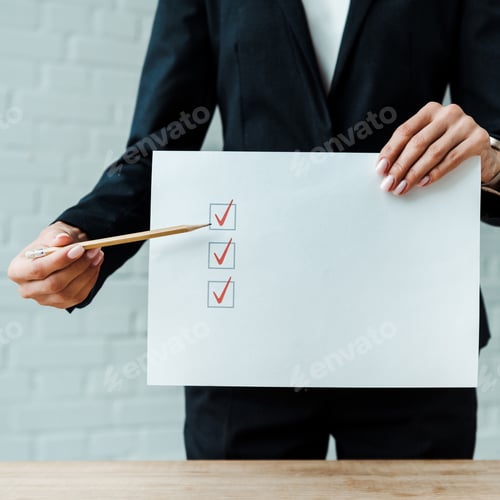 Preview: cropped view of businesswoman holding pencil near paper with check list
