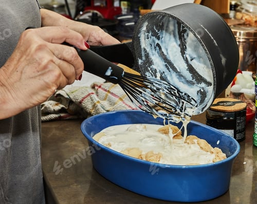 Preview: Chef pours bechamel sauce, cauliflower in ceramic dish for baking in the oven